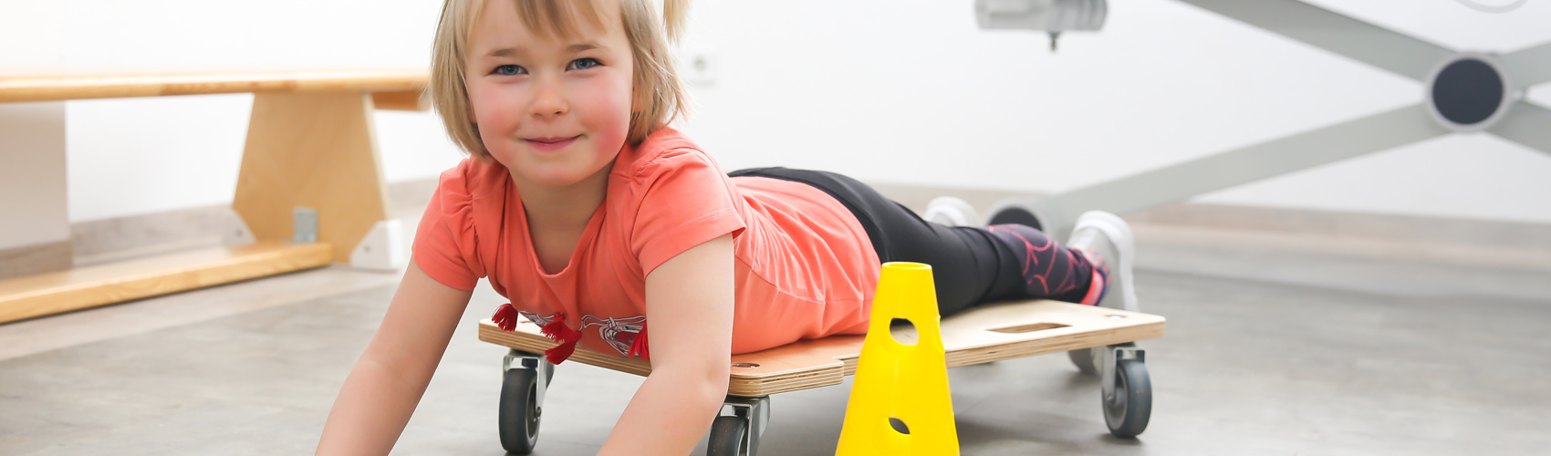 Mädchen auf Rollbrett im Behandlungsraum